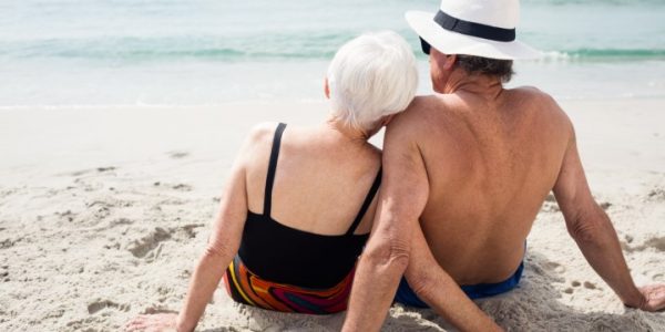Rear view of senior couple sitting on beach on a sunny day